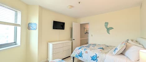 A bedroom with two beds, a dresser, a television, and a window with blinds.