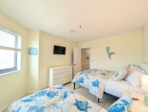 A bedroom with two beds, a dresser, a television, and a window with blinds. - Ocean Front 2 BR | Myrtle Beach Resort - RT1902 (Myrtle Beach)