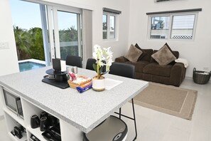 Una sala moderna con comedor, piscina y balcón con vistas al follaje.