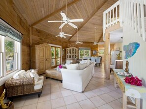 A spacious room with a high ceiling, multiple ceiling fans, a white sofa, a wicker sofa, and a dining area with a table and chairs. - Shangri-la & Cottage · Tropical Beach Villa With Guest Cottage 5 Bedroom Villa (Governor's Harbour)