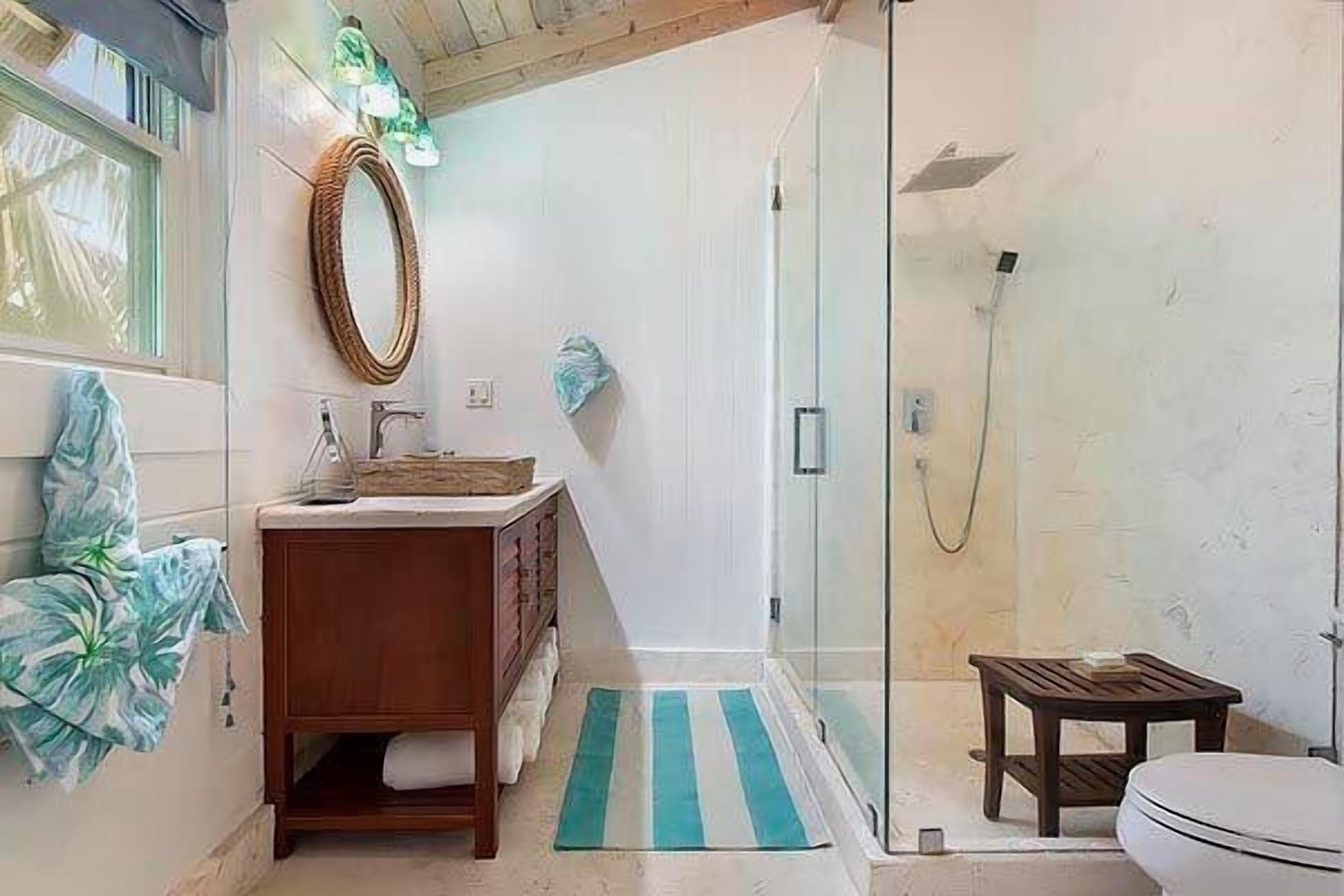A bathroom with a glass-enclosed shower, a wooden vanity, and a toilet.