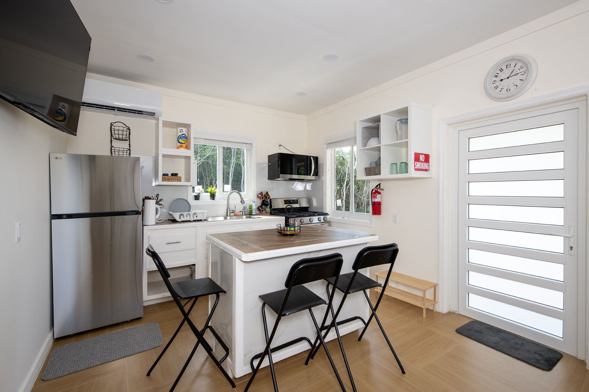 A compact kitchen with a refrigerator, stove, microwave, and a small dining area with chairs.