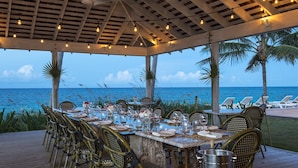 An outdoor dining area with a view of the ocean, wooden deck, and wicker chairs. - Eagle Ray - Brand New Beach Cottage W/views, Walk To Restaurant/ 2 Bedroom Home (North Palmetto Point)