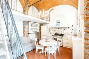 A modern kitchen with white cabinetry, a gas stove, and a dining area with a round table and white chairs. - Porta Romana. The Charm of Florence: Close to Downtown and Far from the Hustle and Bustle (Firenze)