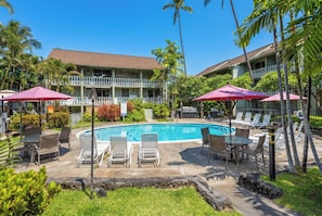 Ein Hotel mit Schwimmbad, Liegestühlen und Sonnenschirmen.