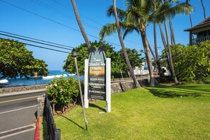 A sign for Kona Islander Inn with a view of the ocean and palm trees. - Kona Islander Inn#251: Downtown Kona, Remodeled, Ocean view, Best Spot (Kailua Kona)