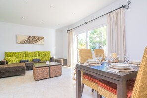 Ein modernes Wohnzimmer mit einer Couch, einem Couchtisch und einem Esstisch, gedeckt für eine Mahlzeit.