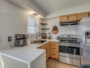 A modern kitchen with white subway tiles, wooden cabinets, a stainless steel refrigerator, and a built-in oven.