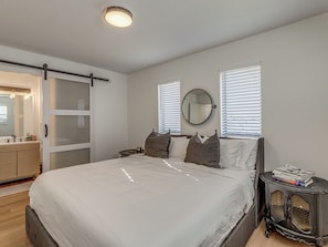 A bedroom with a bed, a dresser, a bedside table with books, a mirror, and a sliding door. - 3-bedroom home in charming Midwest City with AC and fitness room (Midwest City)