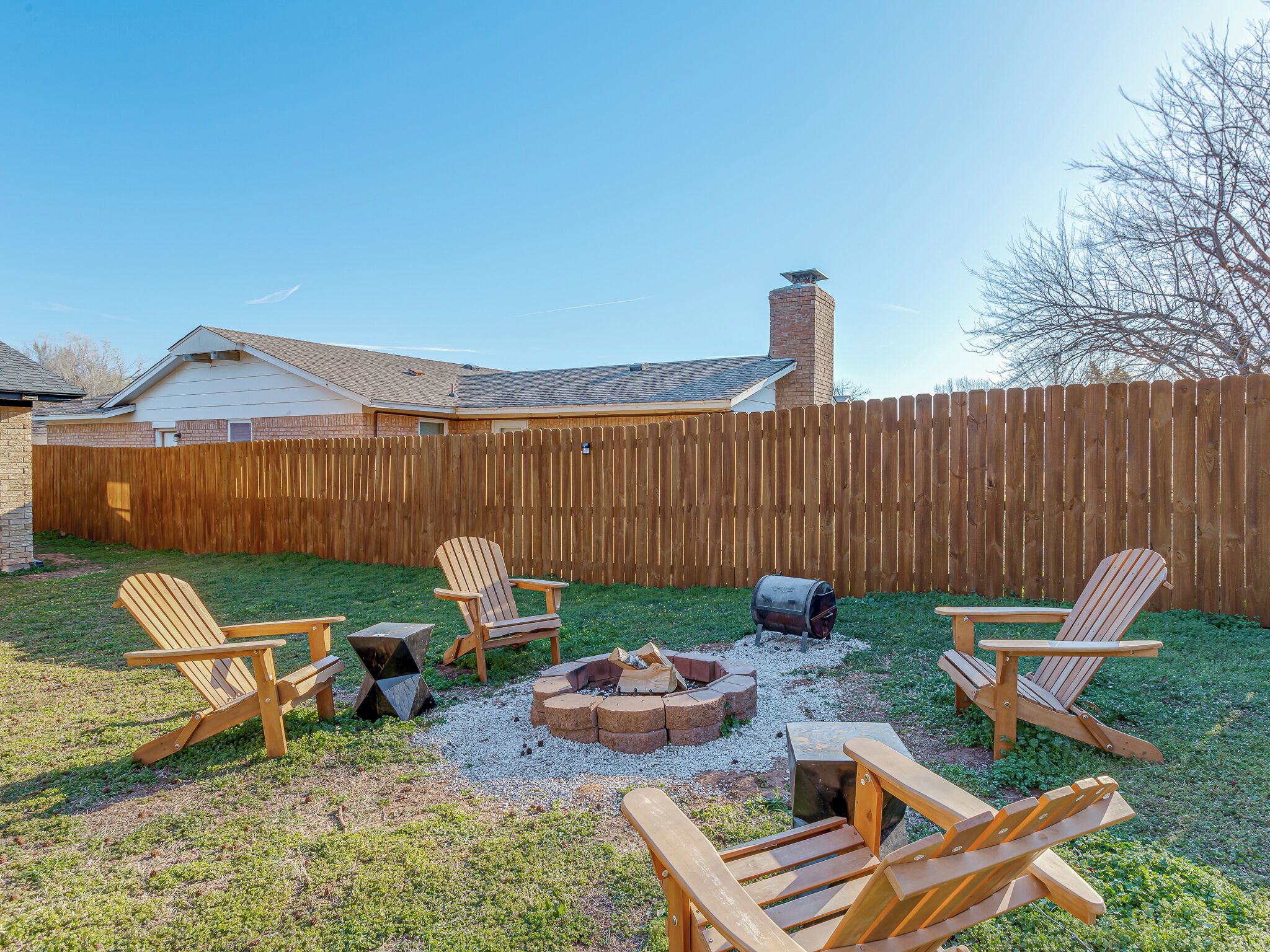 Un jardin avec une terrasse en bois, un espace salon extérieur et un foyer.