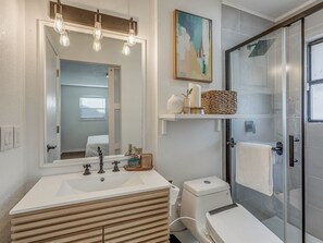 A bathroom with a large mirror, a shower, and a vanity with a sink and multiple faucets. - 3-bedroom home in charming Midwest City with AC and fitness room (Midwest City)