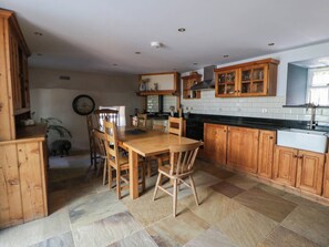 A kitchen with wooden cabinets, a dining table, and chairs. - Yr Hen Felin (Boncath)