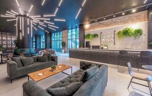 Eine moderne Lobby mit Empfangstresen, Sitzgelegenheiten und großen Fenstern.