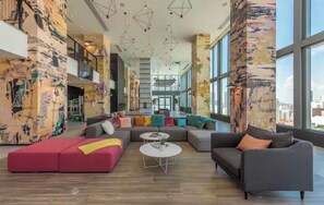 Eine geräumige Lobby mit einer Eckcouch, einem roten Hocker und einem Couchtisch.