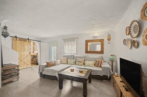 A living room with a sofa, a coffee table, a television, and a wall-mounted mirror.