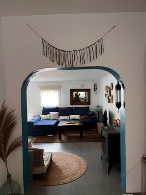 Un salon avec un canapé bleu, une table basse et une cheminée.