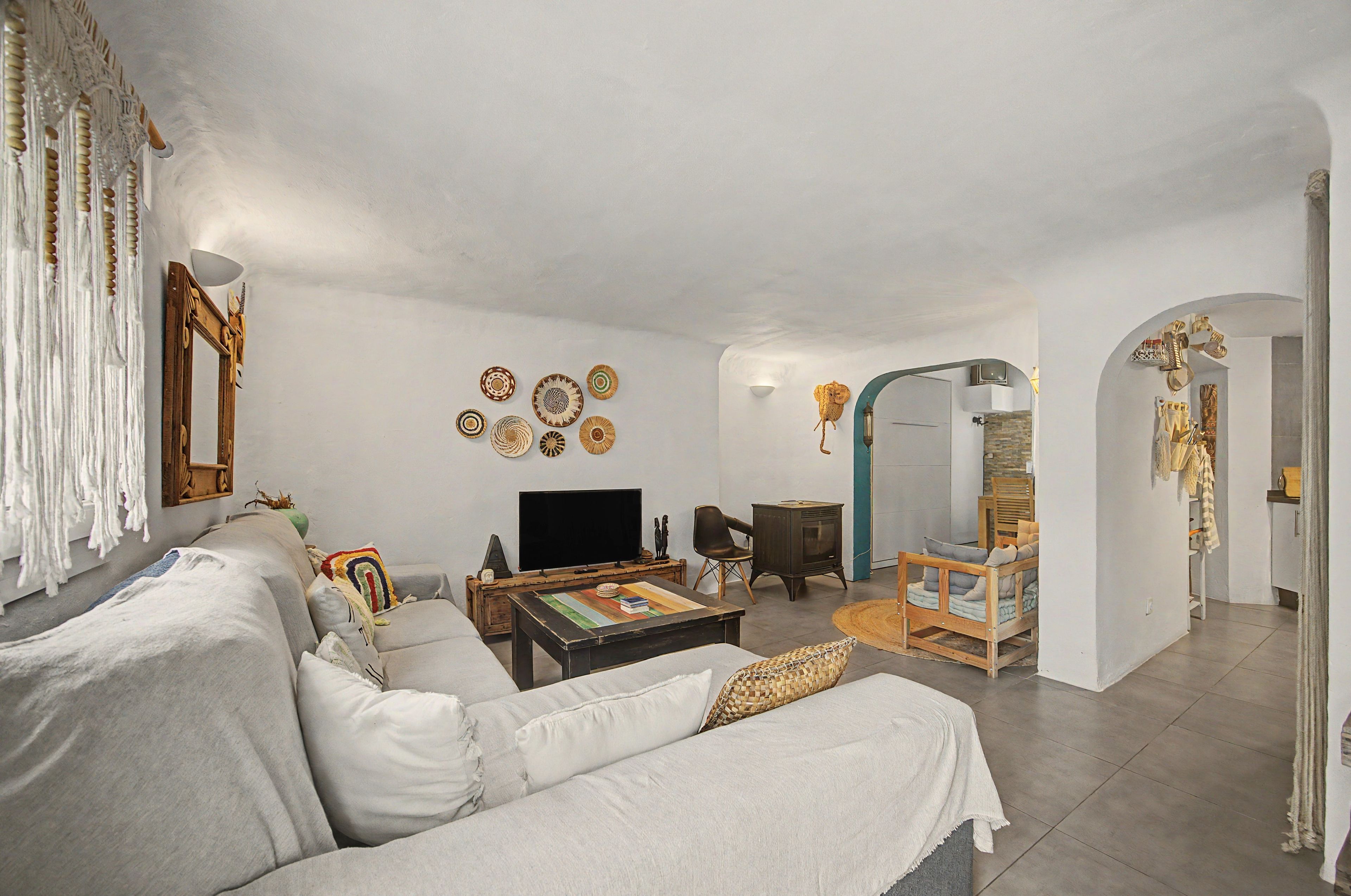 A living room with a sofa, coffee table, television, and decorative plates on the wall.