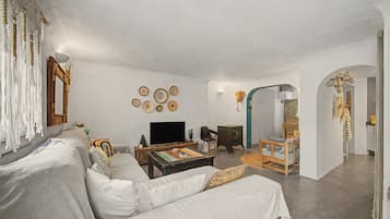 A living room with a sofa, coffee table, television, and decorative plates on the wall.