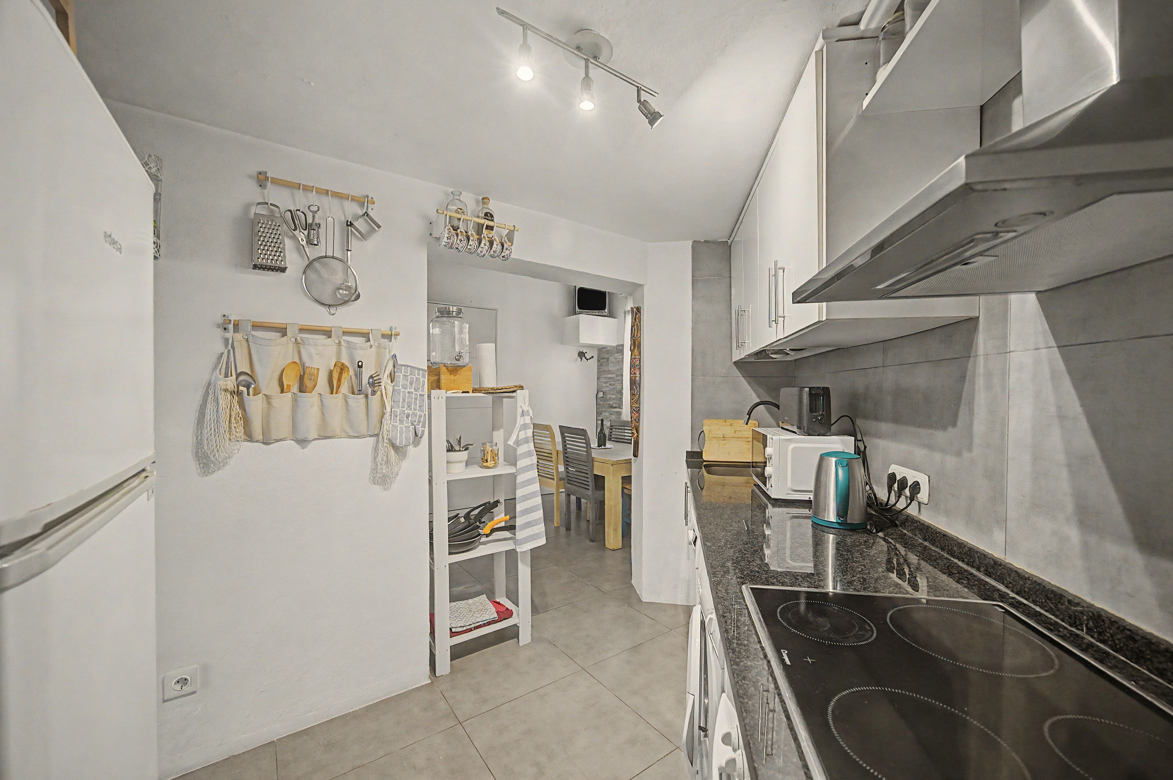 Una cocina con estufa, microondas y varios utensilios en la pared.