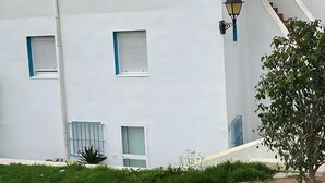 Ein weißes Gebäude mit zahlreichen Fenstern, einer Satellitenschüssel und einer Treppe, die zu einer oberen Ebene führt.