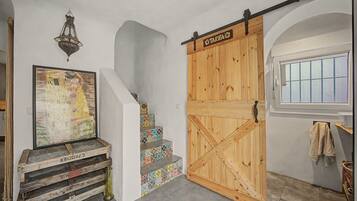 Eine Treppe mit farbenfrohen Fliesen, eine mit 'TARIFA' beschriftete Holztür und ein gerahmtes Gemälde an der Wand.