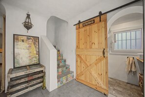 A staircase with colorful tiles, a wooden door labeled 'TARIFA', and a framed painting on the wall.