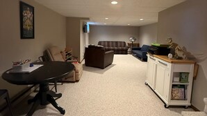 Ein Wohnzimmer mit einem schwarzen Tisch, einem braunen Sofa, einem blauen Sofa und einer weißen Kommode mit Dinosaurerfiguren.