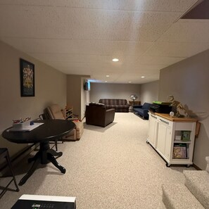 A living room with a black table, a brown sofa, a blue sofa, and a white cabinet with dinosaur figures. - New - Lake Ida Cabin (Lake Park)