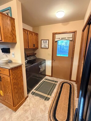 A kitchen with wooden cabinets, a stove, and a window with a view of a deck. - New - Lake Ida Cabin (Lake Park)
