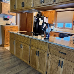 A kitchen with wooden cabinets, a black refrigerator, and a granite countertop. - New - Lake Ida Cabin (Lake Park)