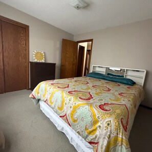 A bedroom with a bed, a dresser, and a door. - New - Lake Ida Cabin (Lake Park)