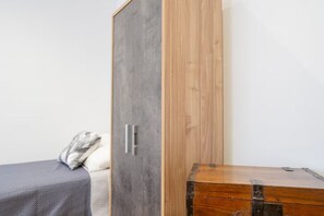 Een slaapkamer met een bed, een kledingkast en een houten kist.