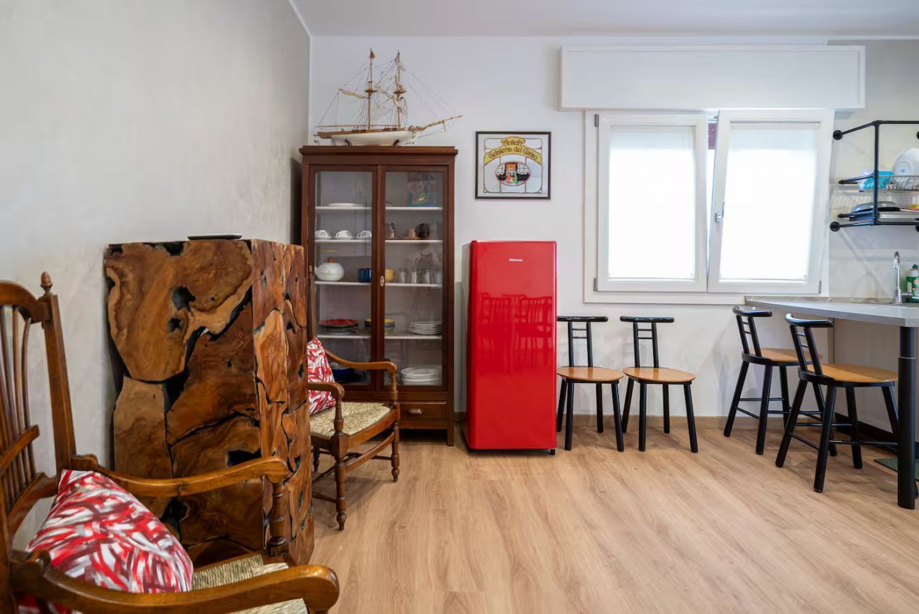 Ein Zimmer mit einem Holzkasten, einem roten Kühlschrank und einem Essbereich mit Stühlen und Tischen.