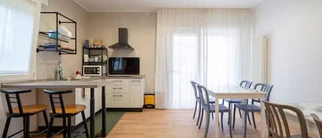 A modern kitchen with a microwave, stove, and dining area with chairs and a table.