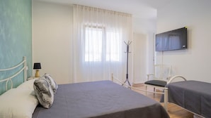 Ett hotellrum med två sängar, en tv, en klädställning och en stol.