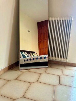 A room with a bed, a radiator, and a wooden wardrobe. - Kastelia Monemvasia (Monemvasias)