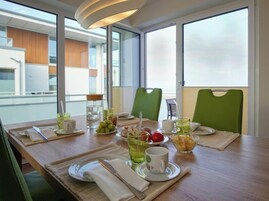 A dining table set with plates, cutlery, and various beverages, with a view of the outside through large windows.