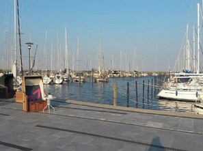 A marina with multiple sailboats docked, a small kiosk, and a clear sky. - Holiday Apartment With 2 Bedrooms (Heiligenhafen)