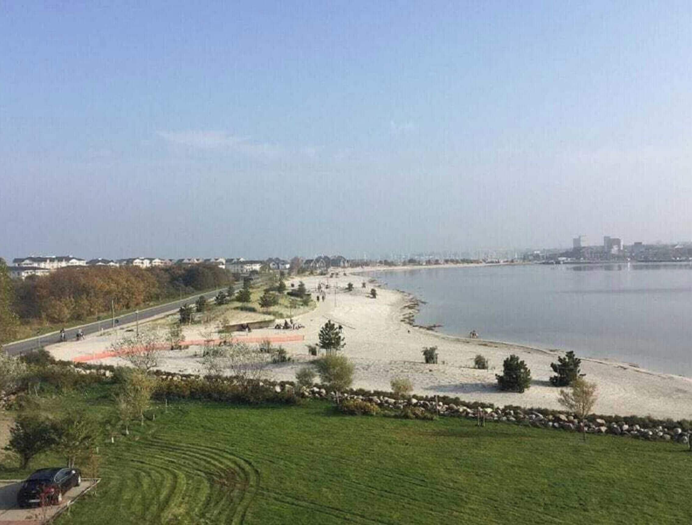 Eine Küstenlandschaft mit Strand, einer Straße und einem Gewässer.