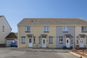 A row of two-story residential buildings with a consistent architectural style, featuring symmetrical windows and doors, and a flat roof. - Comfortable Home, Garden & Parking, Walk to Beach! (Westward Ho)