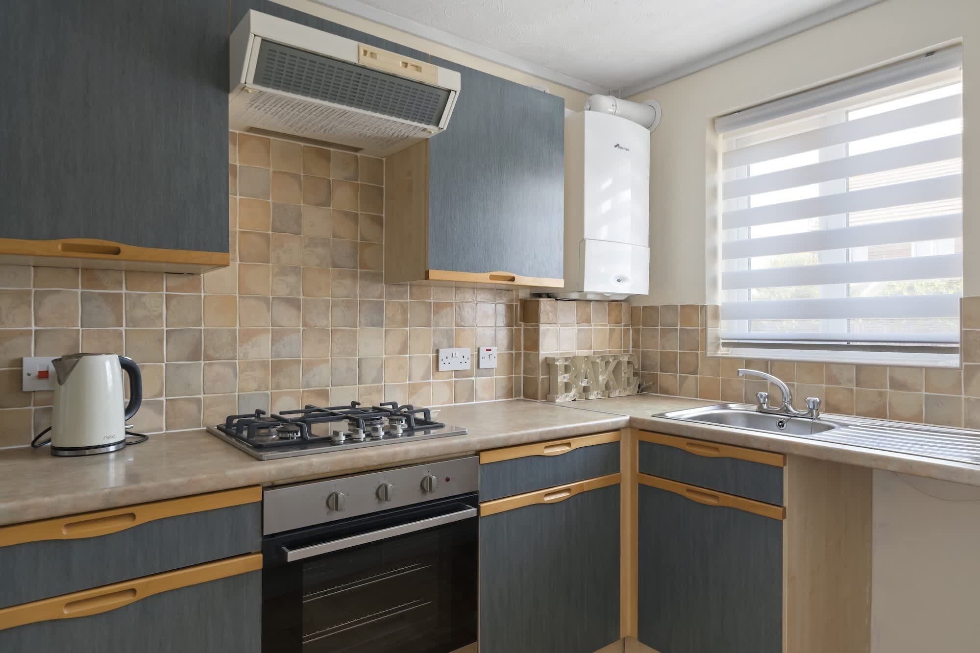 A kitchen with a gas stove, oven, and a window with blinds.