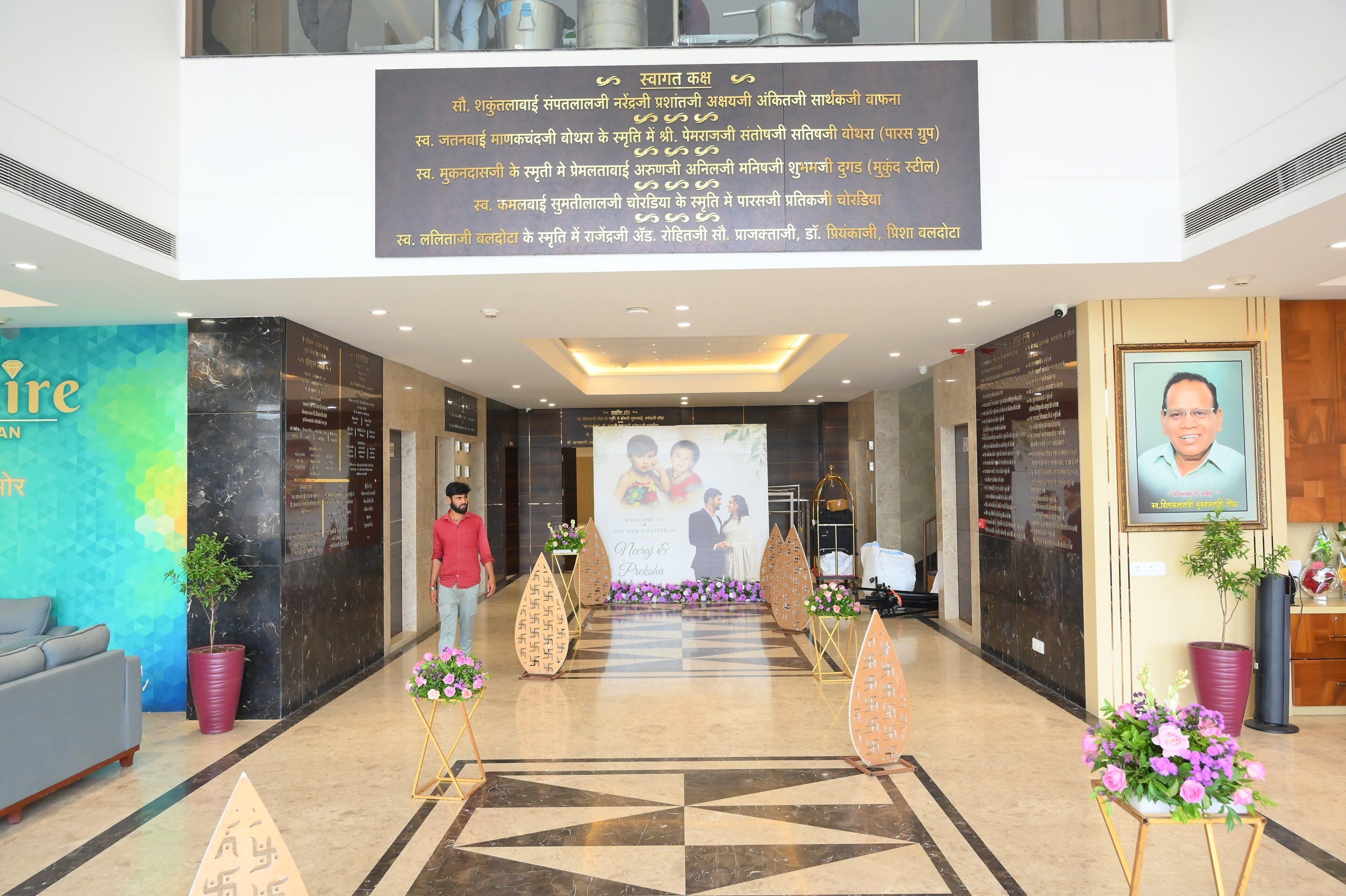A hotel lobby with a large welcome banner, a reception desk, and a seating area with a sofa.