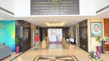 A hotel lobby with a large welcome banner, a reception desk, and a seating area with a sofa.