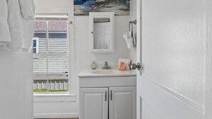Casa de banho com lavatório branco, espelho e porta-toalhas.