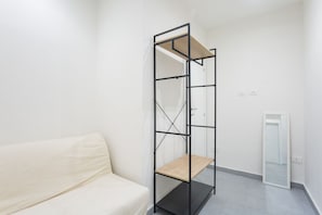 A minimalist room with a white sofa, a black metal shelf unit, and a white door. - O' Buvero Suite Apartment By Dimorra  (Naples)