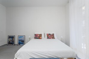 A bedroom with a bed, two pillows, two bedside tables, and two framed pictures on the wall. - O' Buvero Suite Apartment By Dimorra  (Naples)