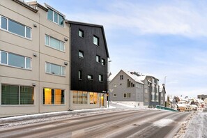 A residential street with modern buildings, a clear sky, and a snow-covered road. - Central Storgata Downtown Apartment (Tromsø)