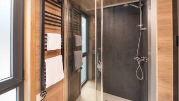 Une salle de bain moderne avec une douche à parois de verre, un lambris en bois et un porte-serviettes.