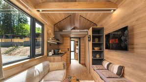 Ein modernes Interieur mit Holzboden, einer Couch, einem Tisch und einem Fernseher, der das Netflix-Logo zeigt.