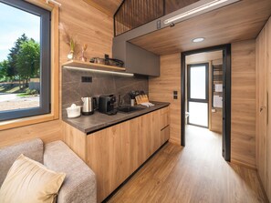 A compact kitchen with a marble backsplash, wooden cabinets, and modern appliances.